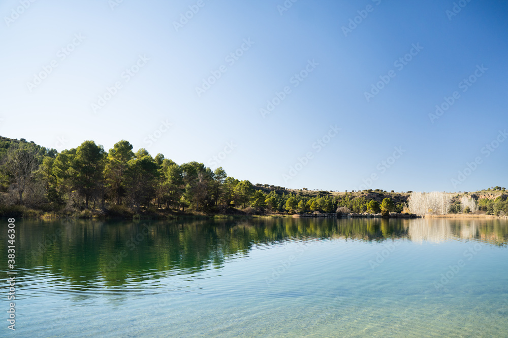 Beautiful and calm lagoon with trees in the background in the natural park of 'Lagunas de Ruidera' in Ossa de Montiel, Albacete, Spain