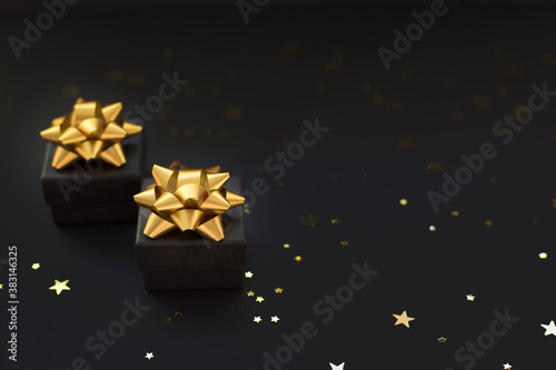 Close up two black boxes of gifts on a black background with gold stars. Black Friday super sale.Selective focus