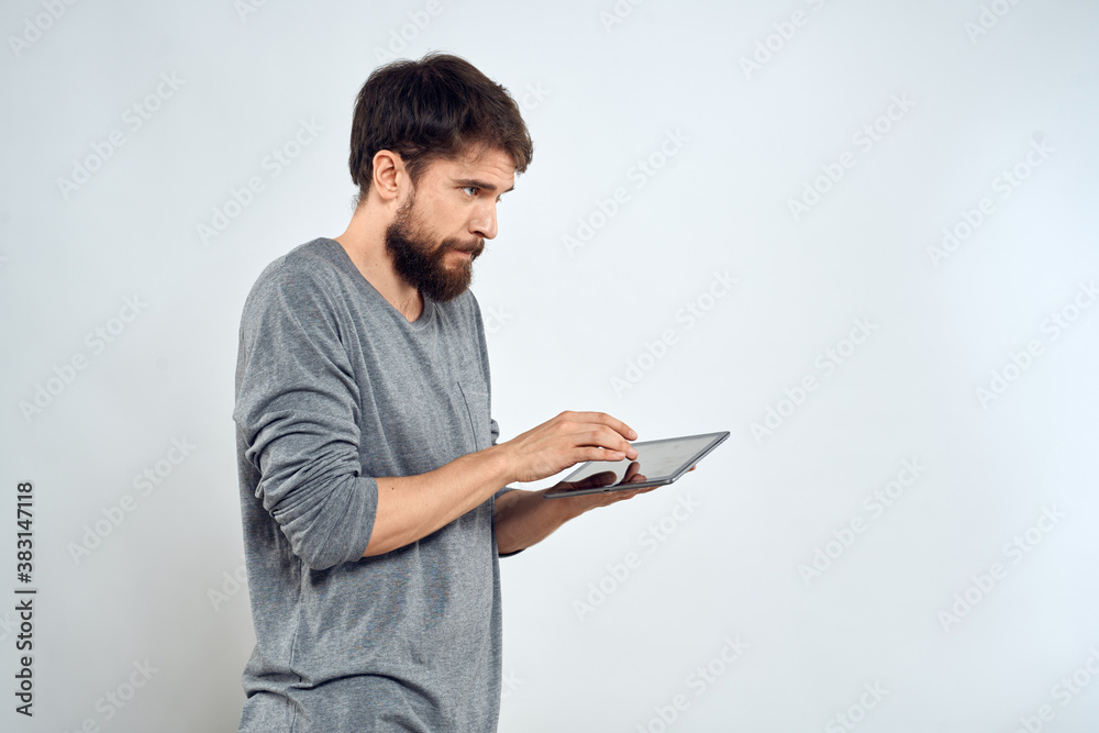 A man with a tablet in his hand internet technology communication gray jacket light background