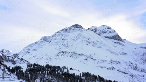 Mountain peak in austrian alps. Iced and snow covered walls with trees.  Beautiful sky view with rural background and winter landscape