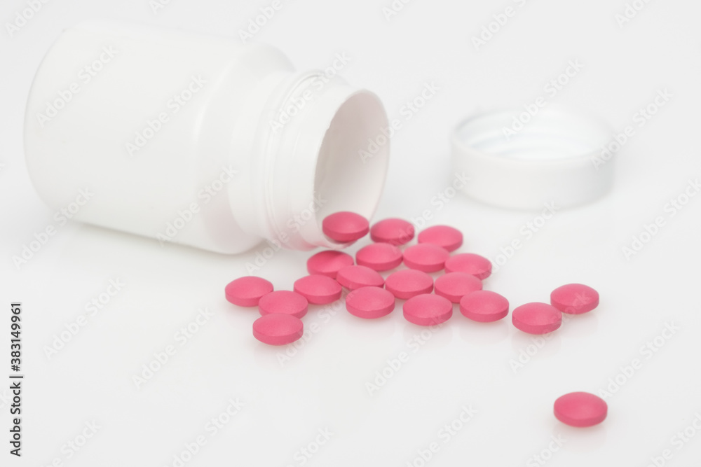 On the white surface is a jar of pills that have spilled out. On the white surface is a jar of pills that have spilled out.