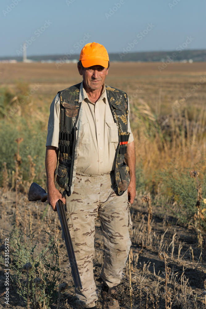 Duck hunter with shotgun walking through a meadow. Duck hunter with shotgun walking through a meadow.