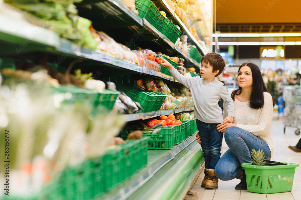 woman and child boy during family shopping with trolley at supermarket woman and child boy during family shopping with trolley at supermarket
