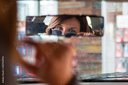 girl looking over glasses in rearview mirror (ID: 383156936)