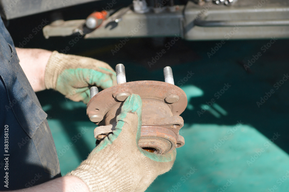 A car mechanic holds a hub in his hands