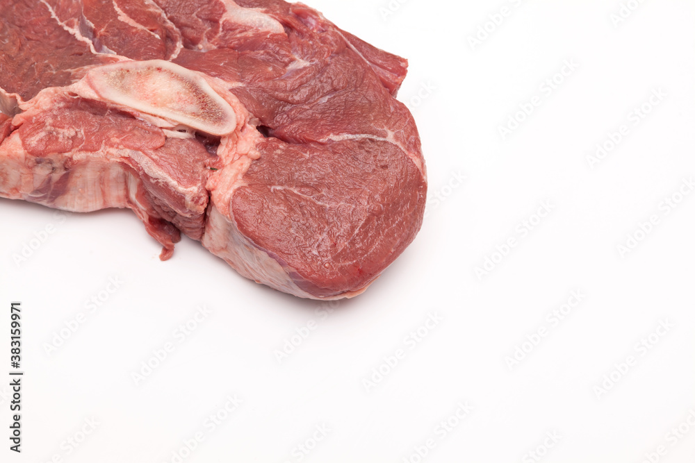 Fresh large piece of meat. Juicy beef with a bone for broth on a light background. Close-up, copy space Fresh large piece of meat. Juicy beef with a bone for broth on a light background. Close-up, copy space