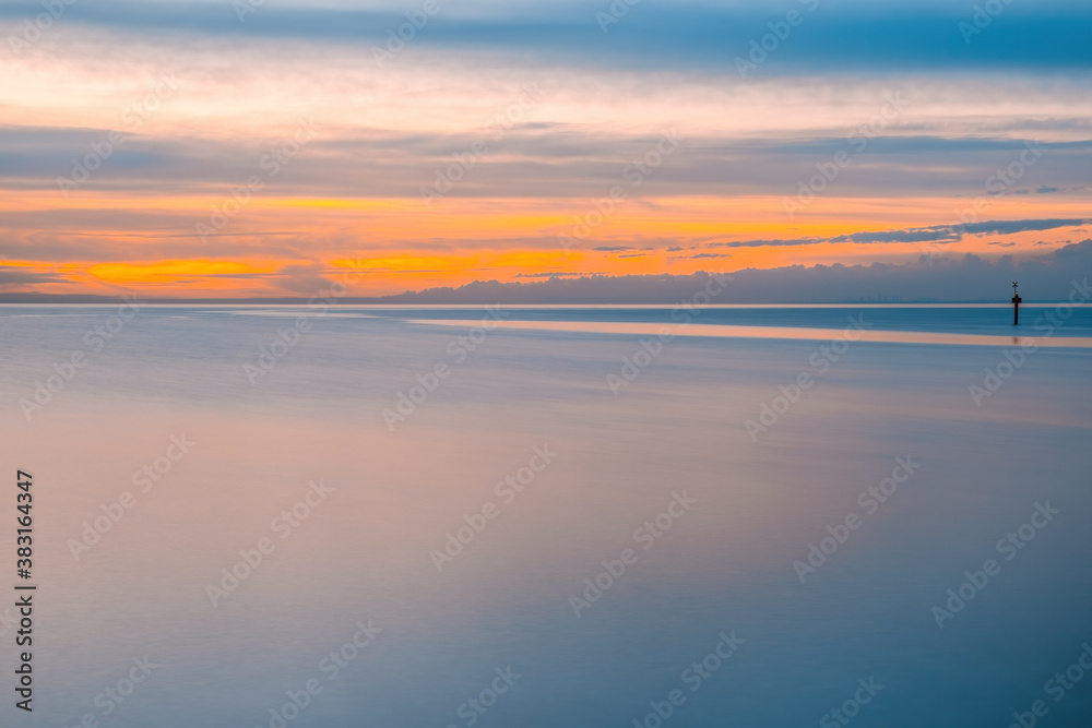 Silky smooth water at sunset over ocean with copy space