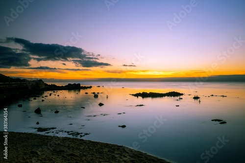 Calm bay water with rocks silhouettes at dusk