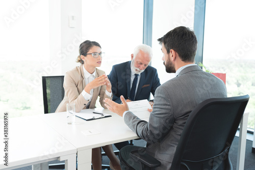 Business people interviewing male applicant at office