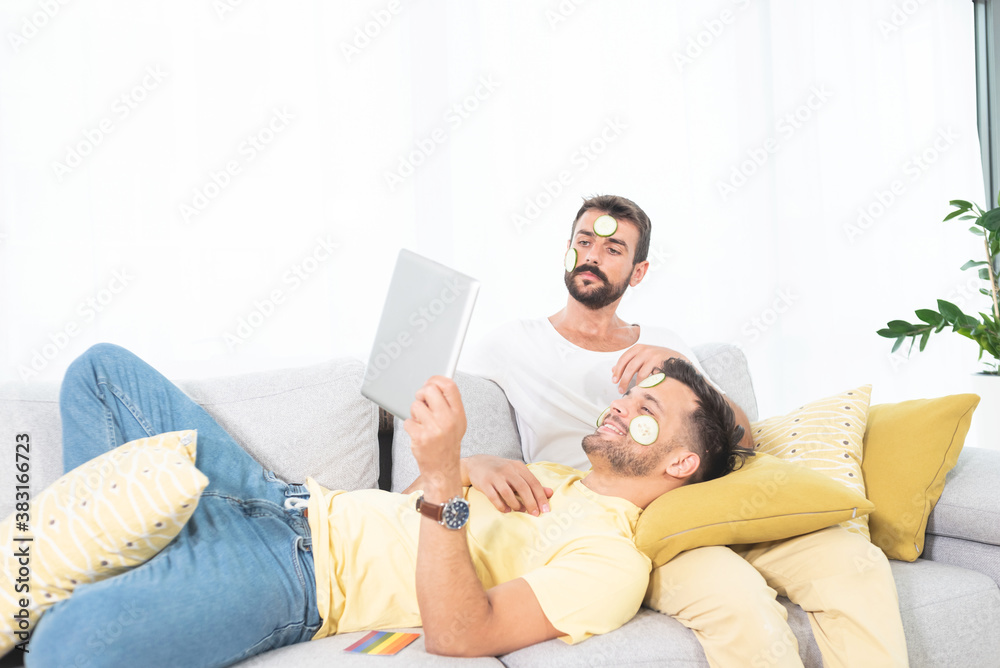 Gay couple with cucumber face mask on sofa Gay couple with cucumber face mask on sofa