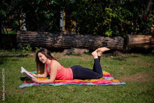 Woman reading a book while lying in the front yard