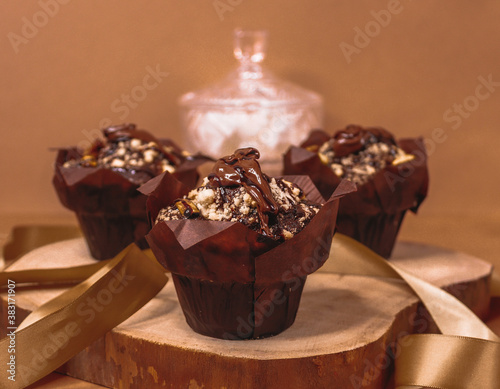 chocolate muffins with nuts...

Chocolate muffins with nuts lie on a wooden frame, close-up side view.