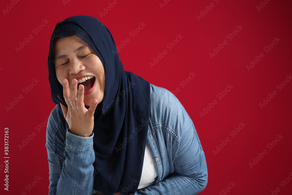 Portrait of muslim lady wearing hijab laughing hard, happy expression, close up head shot against red