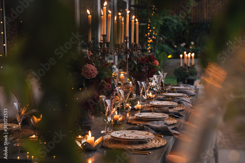Christmas table with candles, flowers and glass cups.