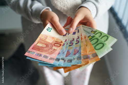Close up on hands of unknown caucasian woman holding and counting a pile of money EURO EUR banknotes counting salary receiving raise or preparing to pay bills