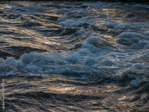 Φωτογραφία Close of shot of river water rippling and flowing golden light.