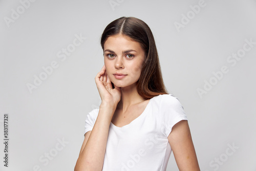 A brunette with long hair holds a hand near the face, a white t-shirt  © SHOTPRIME STUDIO