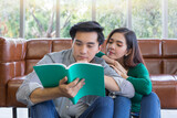 Asian man and woman reading book in living room
