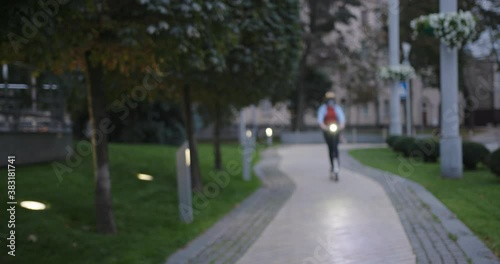 Wallpaper Mural Stylish woman in protective mask rides e-scooter with flashlight along green city park in evening and stops at camera slow motion Torontodigital.ca
