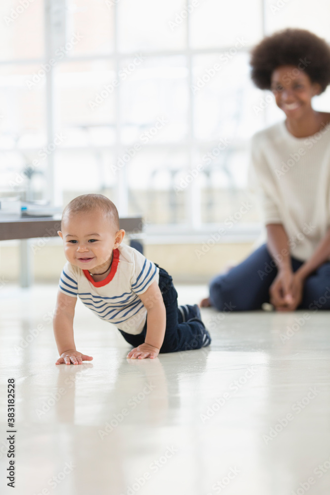 Fototapeta premium Mother watching cute baby boy crawling on floor