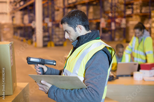 Tablou pe pânză Male worker scanning box in distribution warehouse