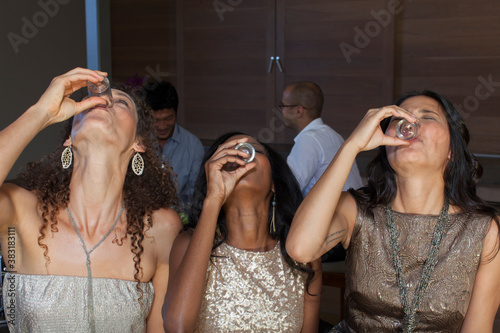 Photography Young women friends taking tequila shots at party