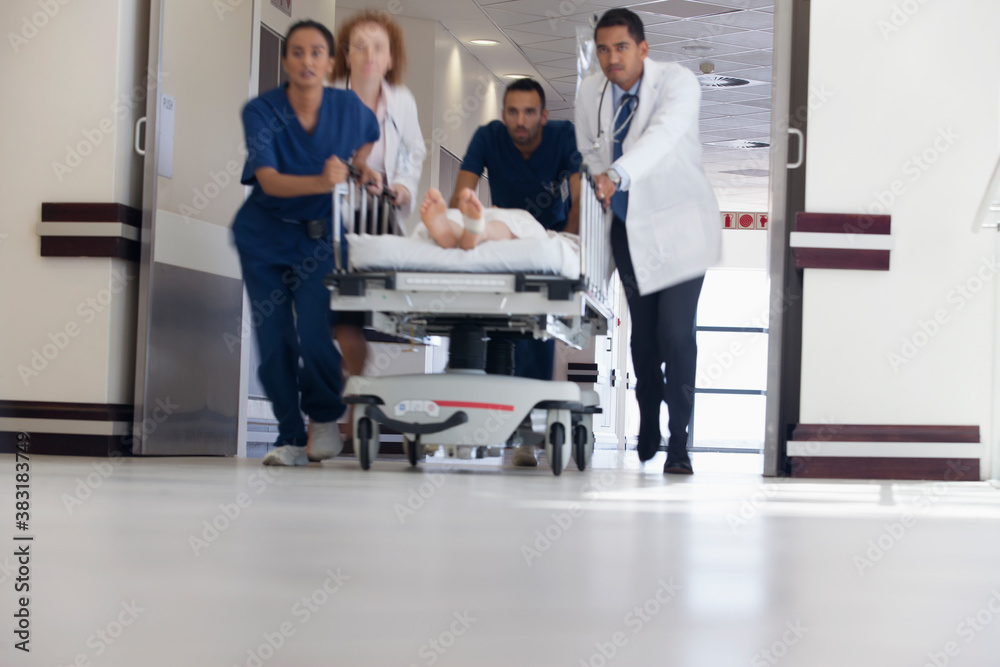 Fototapeta premium Doctors and nurses rushing patient on stretcher in hospital corridor