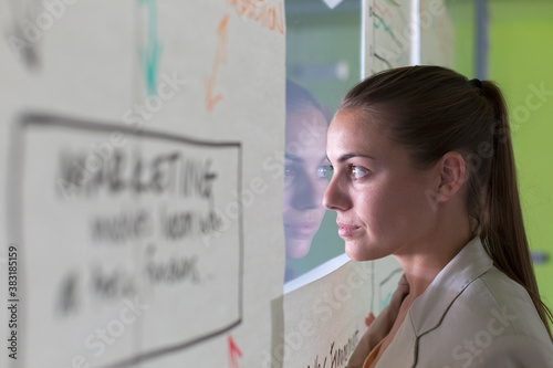 Thoughtful creative businesswoman peering out window