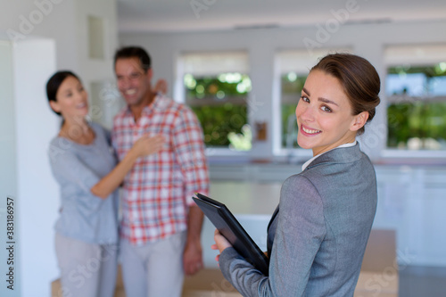 Portrait confident realtor with couple in new house
