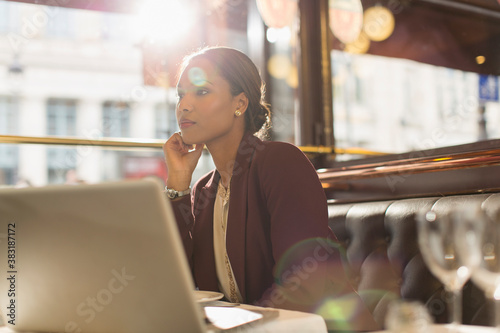 Valokuva Serious businesswoman with laptop working in sunny restaurant