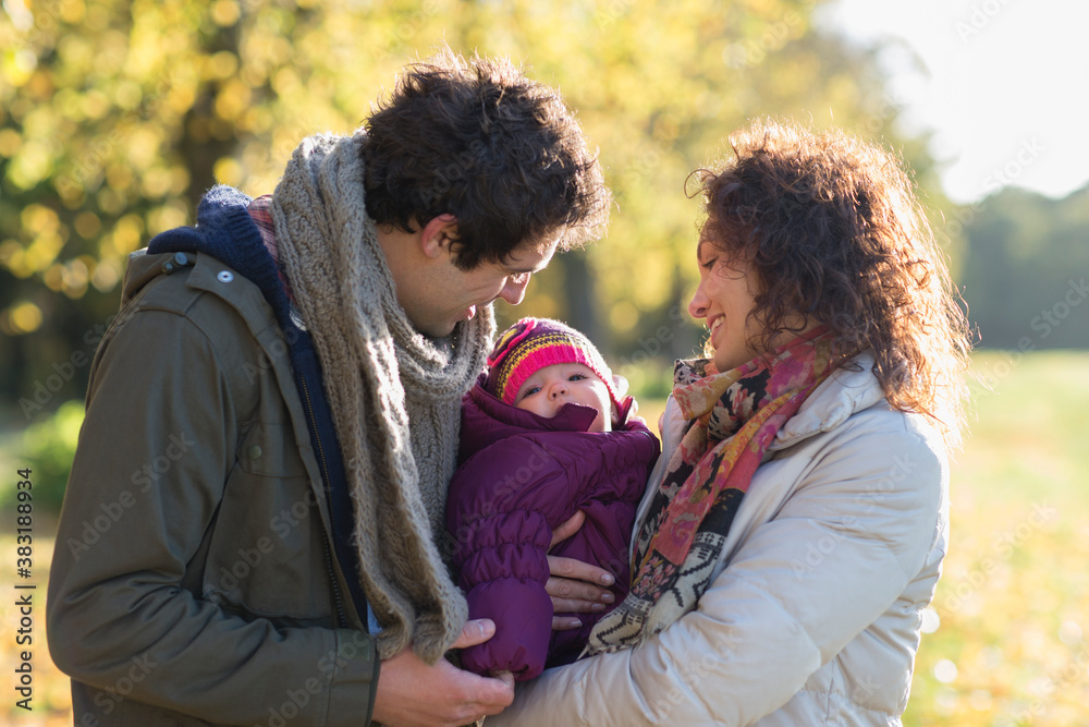 Fototapeta premium Happy young couple holding baby daughter in sunny park