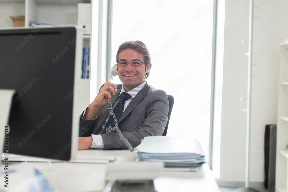 Fototapeta premium Portrait confident businessman talking on telephone at computer