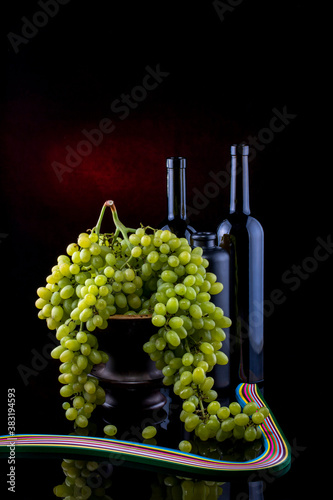 Still life with ripe grapes and glass bottles
