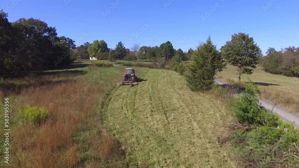 An aerial of a farmer cutting his pasture with a brush hog mower An aerial of a farmer cutting his pasture with a brush hog mower