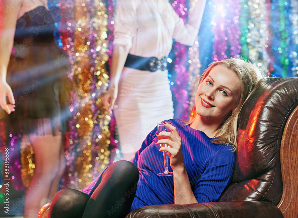 Happy relaxed woman with glass of sparkling wine resting in night club