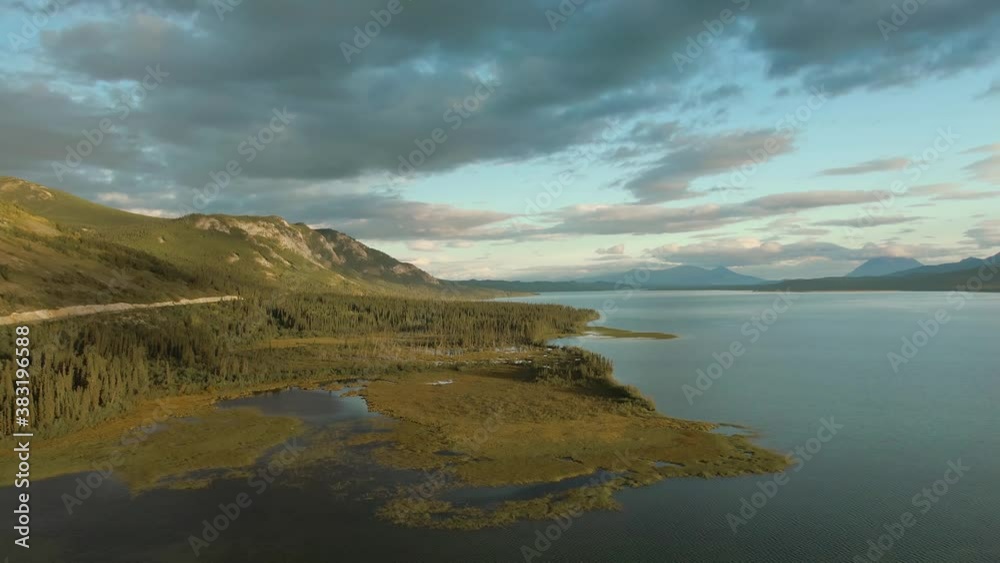 Gorgeous View of Peaceful Lake and Mountains at Sunset in Canadian Nature. Aerial Drone Shot. Taken near Atlin, Yukon, Canada. Gorgeous View of Peaceful Lake and Mountains at Sunset in Canadian Nature. Aerial Drone Shot. Taken near Atlin, Yukon, Canada.