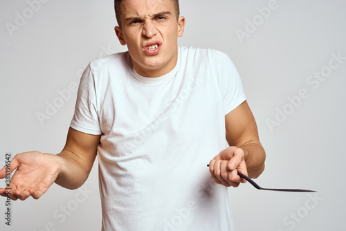 Guy with kitchen tools in hands on a light background cropped view of emotions fun model