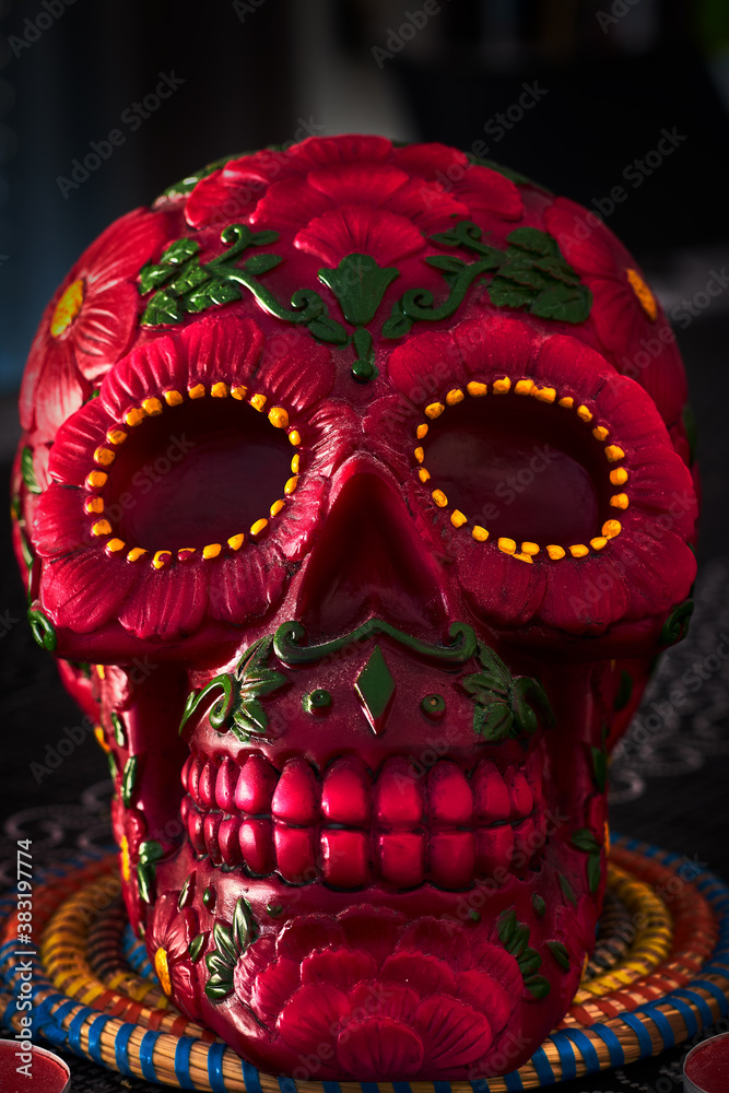 Mexican day of the dead skull with red and green daisies and red teeth