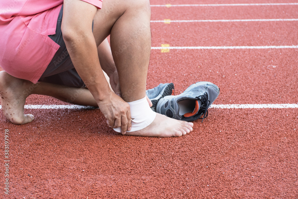 man applying compression bandage onto ankle injury After exercise