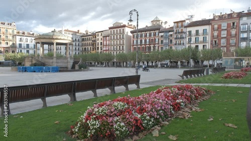 Flowers and garden in the Plaza del Castillo (Castillo Square) in Downtown Pamplona with unrecognizable masked passerby photo