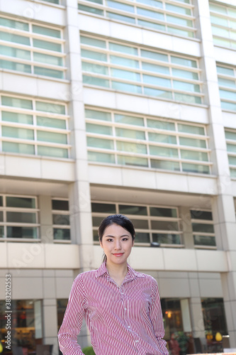 Young south east Asian middle woman business colleague in front of a tall building look forward at camera