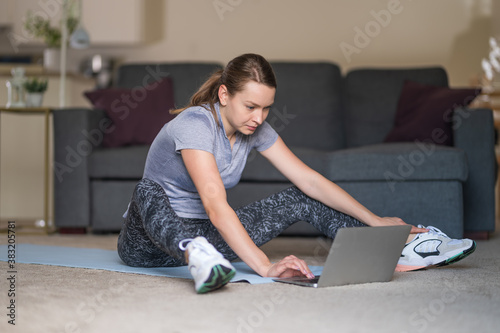 Young fit girl in sportswear doing yoga exercises with mat on the floor in living room at her home. Strong girl body. Care about health. Yoga concept.