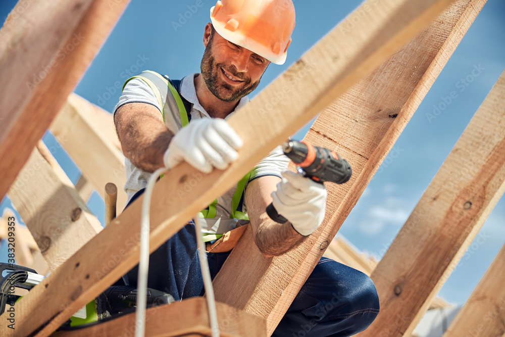 Positive delighted bearded man fixing crews into board Positive delighted bearded man fixing crews into board