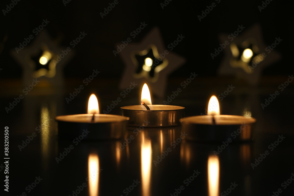 three candles are burning on a dark background. High quality photo three candles are burning on a dark background. High quality photo