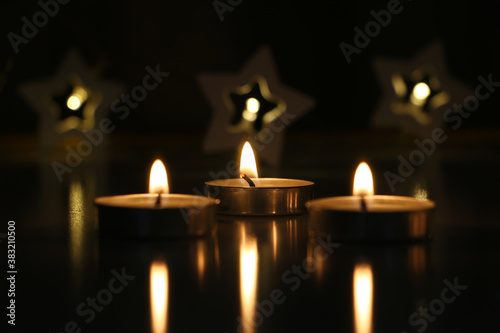 three candles are burning on a dark background. High quality photo
