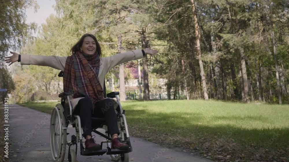 Happy cheerful disabled woman in the wheelchair enjoying the walk in the beautiful autumn forest. Woman is laughing and feels exciting Happy cheerful disabled woman in the wheelchair enjoying the walk in the beautiful autumn forest. Woman is laughing and feels exciting