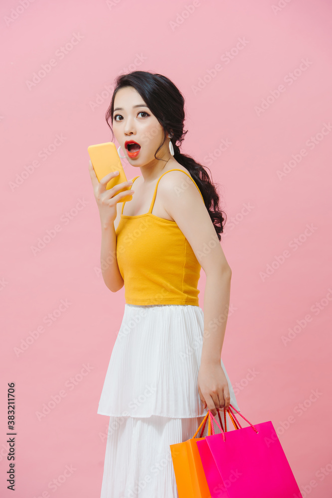 Woman carrying shopping bags and text messaging on the phone