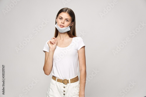 Beautiful brunette with a medical mask on her face and in a white T-shirt 