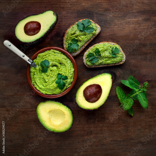 Avocado  on dark  wooden Background.  Guacamole sauce with avocado toast close-up. View from above
