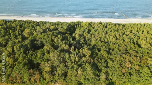 Aerial side movement over the forest, white sand beach, and baltic sea in Kuznica, Pomeranian Voivodeship (north Poland), a district of the seaside town of Jastarnia on a sunny autumn day photo